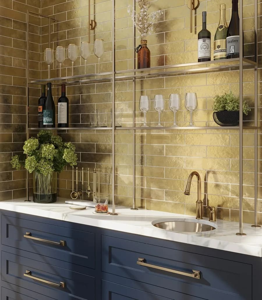 A marble counter with brass fittings under a gold-tiled bar wall