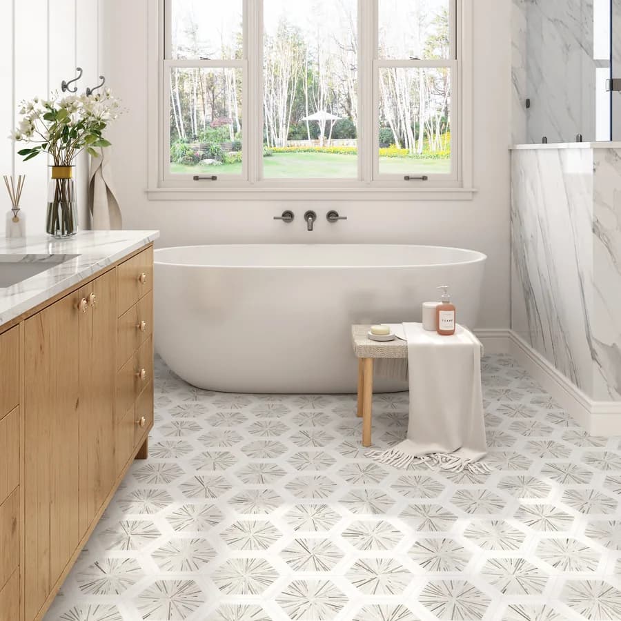 A bathroom floor laid in patterned hexagon tile beside a freestanding tub