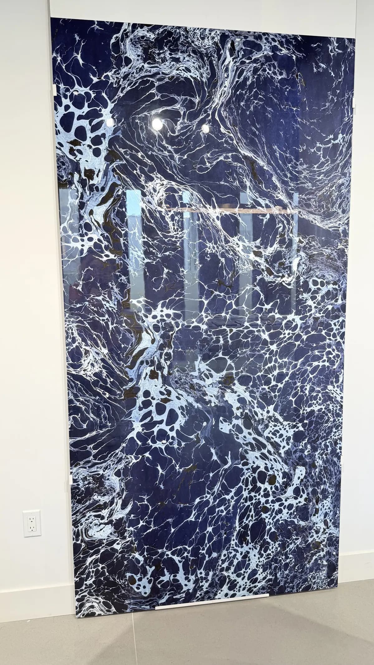 A deep navy and white marble slab standing full height under showroom lighting