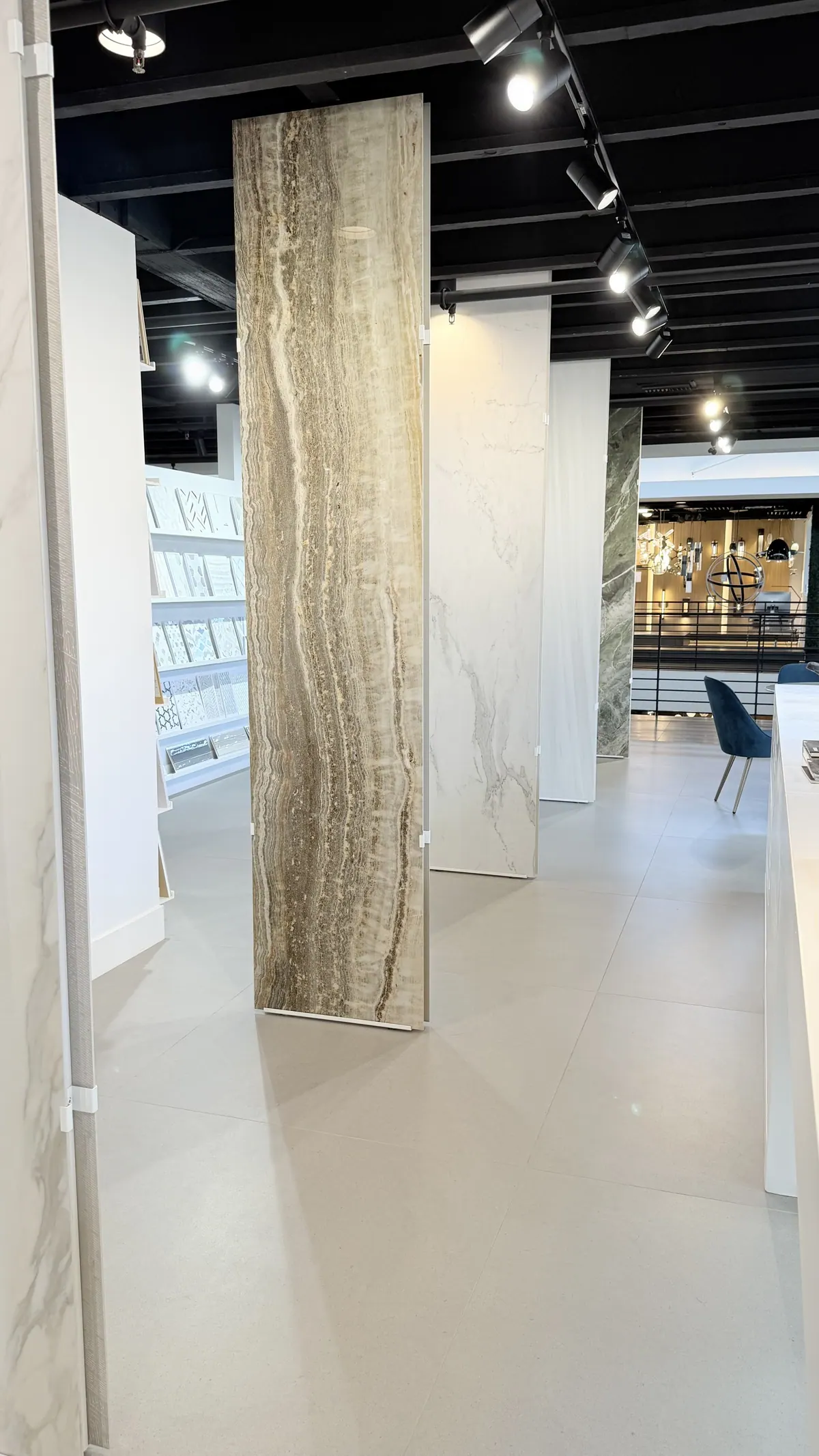 A warm gold travertine slab standing between sample walls